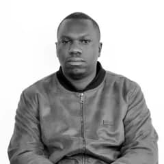 Portrait of David Kubwimana in a dark jacket against a plain backdrop.